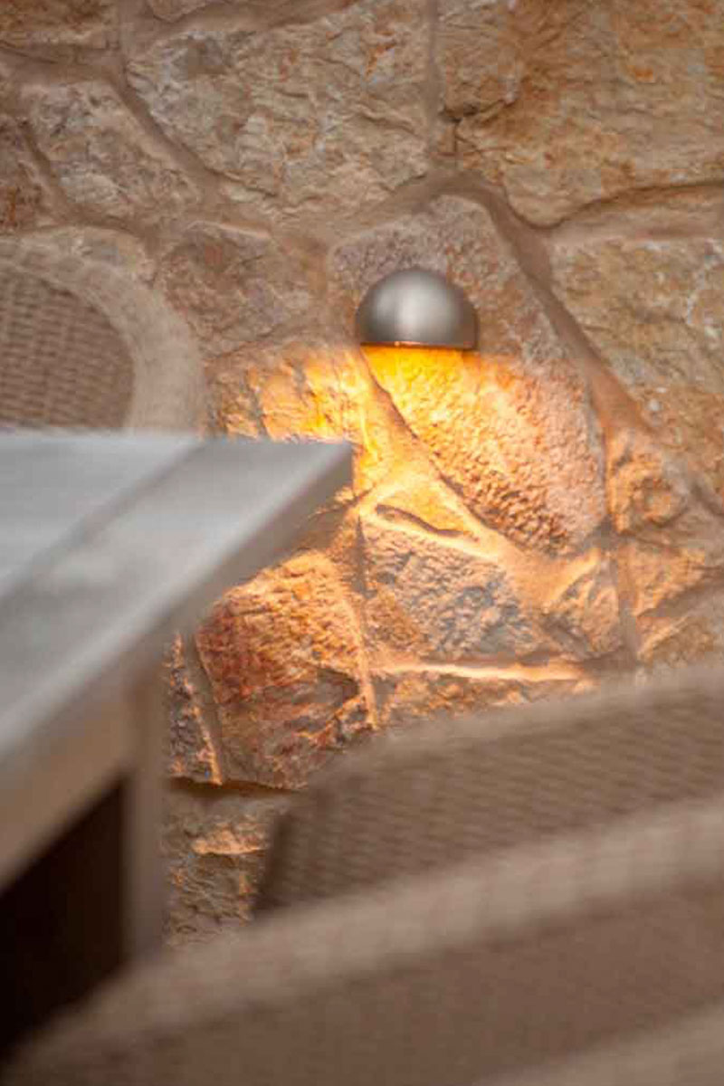 Gardens at Night step light illuminating sandstone wall in dining setting in landscaped garden