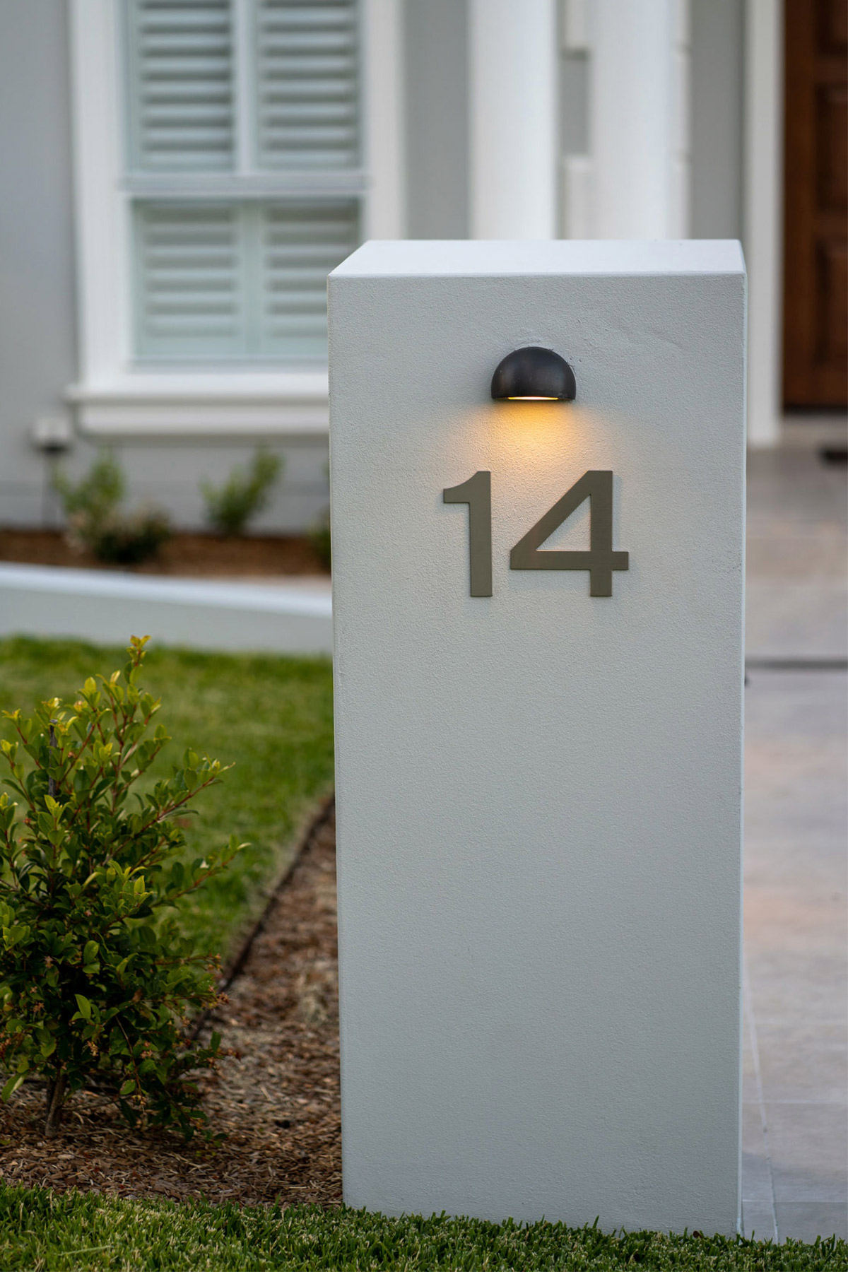 A Gardens at Night Step Light Round in bronze highlighting street number.